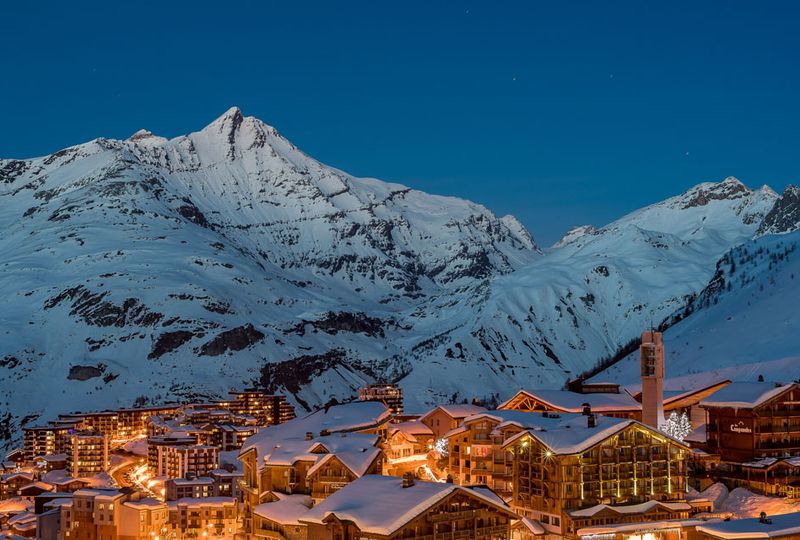A bird's eye view of Tignes at dusk under snow, lights shining